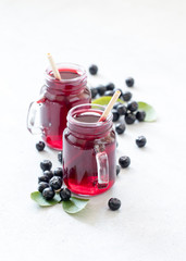 Drink chokeberry in a jar with bamboo straws on a light background