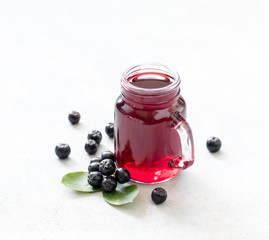 Drink chokeberry in a jar with bamboo straws on a light background