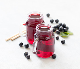 Drink chokeberry in a jar with bamboo straws on a light background