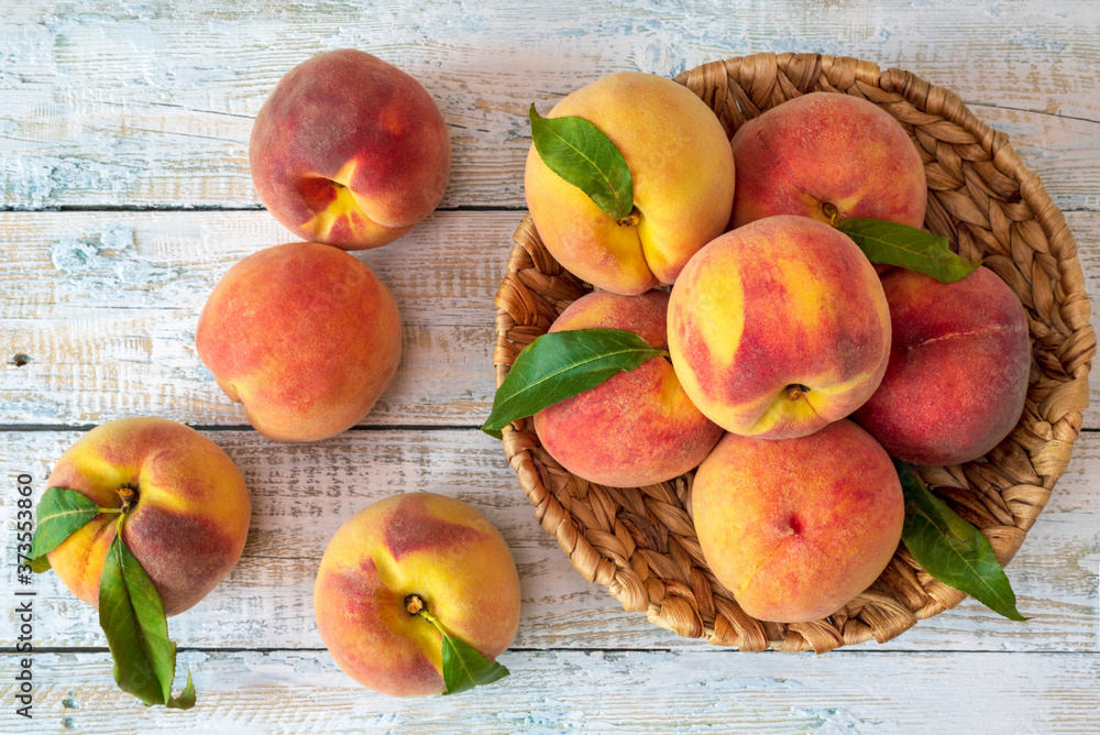 Wall mural ripe peaches on a white rough wooden table. top view.