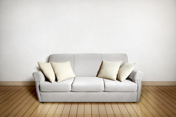 Setting with gray sofa with cushions in front of a white wall and light wooden floor