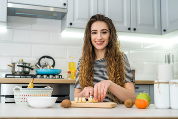 Happy young woman prepare doing fruits salad for diet in kitchen, healthy food