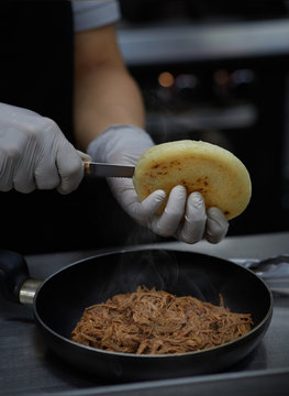 chef preparing Venezuelan arepa stuffed with shredded meat typical food