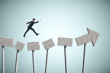 Businessman jumping on concrete arrow