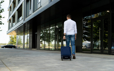 Fototapeta na wymiar Man in casual clothes walking with a suitcase