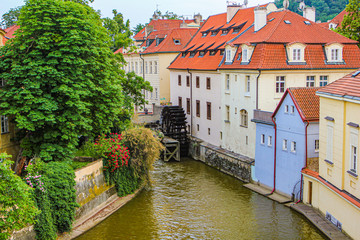 Fototapeta na wymiar Summer European city. View of a cozy courtyard. River channel and water mill