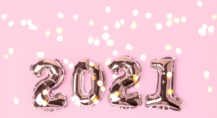 Happy New Year 2021 celebration. Gold balloons in form of numbers with shiny bokeh lights on festive on pink background. Flat lay, top view, banner
