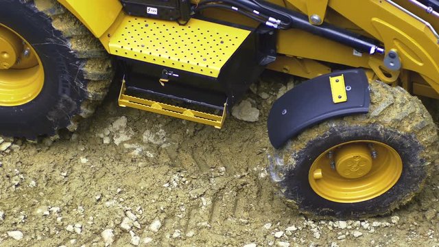 Skid steer loader excavator at road construction work, moving soil at construction site. Closeup 4K
