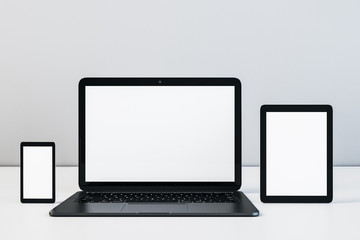 Laptop, digital tablet and cellphone with blank screen on table