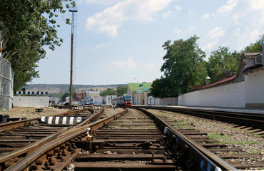 Railway station. View of the rails and wooden sleepers. Trains are visible in the distance. 