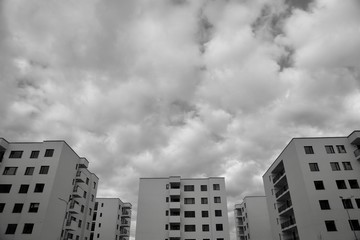 Black and white spectacular view of new apartment buildings in a residential neighborhood, with heavy grey clouds on the sky