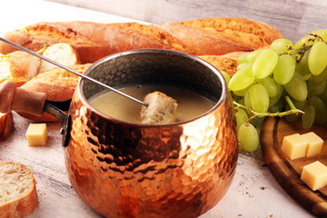 Gourmet Swiss fondue dinner on a winter evening with assorted cheeses on a board alongside a heated...