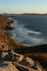 View of the waves breaking when they get to the shore during sunset with famous Galician islands in the background