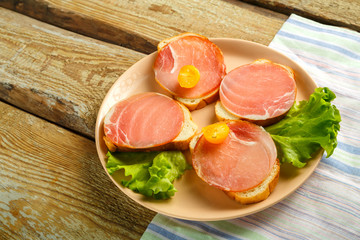 Sandwiches with ham and cherry on a wooden board on a napkin. Copy the place.