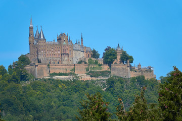 The popular Hohen Zollern castle, lots of green trees, blue sky. Copy space. Germany, Baden-Wuerttemberg.