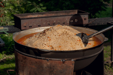 National food of the eastern peoples. Pilaf in a large cauldron. Rice and lamb cooked over the fire. Cooking national food