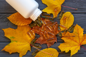 fish oil capsules on yellow autumn leaves. Pharmacy theme - Drug prescription for treatment...