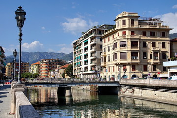 Naklejka na ściany i meble The beautiful Italian town of Rapallo, overlooking the streets of the city with the river, bridges, mountains. The urban landscape in Italy.