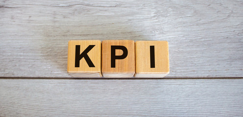 Concept word KPI, 'key performance indicator' on cubes on a beautiful white wooden table. Business concept, copy space.