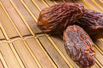 Big luxury dried date fruit on the bamboo mat, kurma ramadan kareem concept, close up.