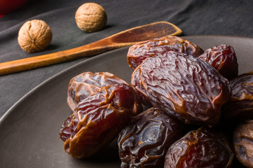 Big luxury dried date fruit in bowls on the dark surface, kurma ramadan kareem concept, close up.