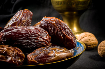 Big luxury dried date fruit in bowls on the dark surface, kurma ramadan kareem concept, close up.