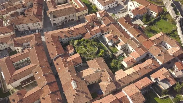 Top down aerial view of a small historic town Venzone in Northern Italy with red tiled roofs of old buildings.
