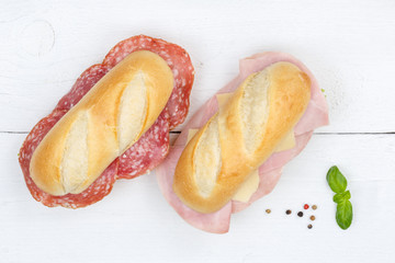 Sub sandwiches baguettes with salami ham and cheese from above on wooden board