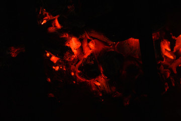 Fototapeta na wymiar red embers of hot fire on blurred background of darkness