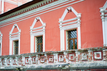 Pale red wall of the Russian church with white windows and metal bars.Decoration of the old...