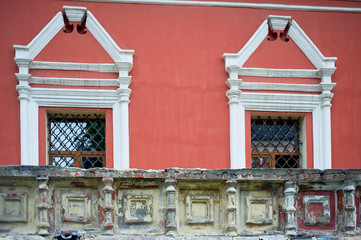 Fototapeta na wymiar Pale red wall of the Russian church with white windows and metal bars.Decoration of the old building.