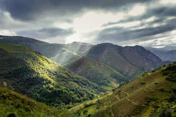 Obraz na płótnie Canvas Los rayos del sol penetran entre las nubes que amenazan tormenta iluminando parte de la montaña en el Parque Natural de Somiedo.