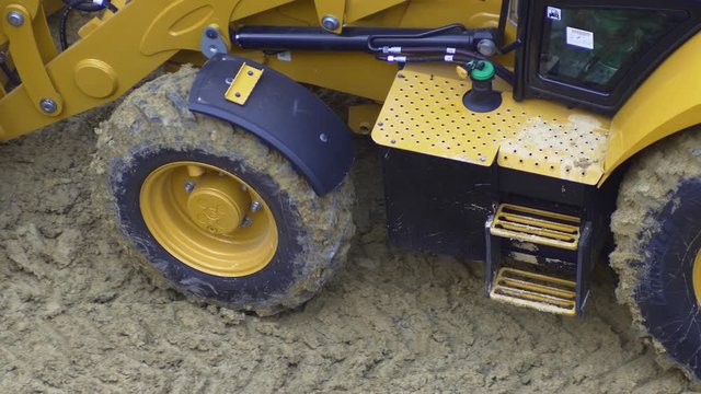 Close up of heavy-duty, off-the-road, all terrain tires for heavy industrial machinery. Moving soil at construction site. Closeup 4K
