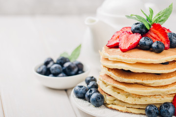 Classic american pancakes with fresh berry on white wood background. Summer homemade breakfast.