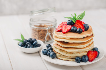 Classic american pancakes with fresh berry on white wood background. Summer homemade breakfast.