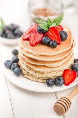 Classic american pancakes with fresh berry on white wood background. Summer homemade breakfast.