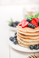 Classic american pancakes with fresh berry on white wood background. Summer homemade breakfast.