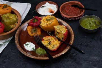 Vegan stuffed peppers with rice, corn grits, vegetables and herbs on clay servingware with side dishes