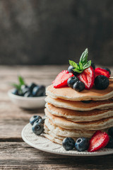 American pancakes with fresh berry on wood background. Summer homemade breakfast.