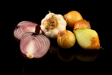 Onions and garlic over black background. Still-life of onions and falling garlic on black background