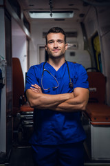 A three quarter portrait of a young handsome paramedic with his hands folded.