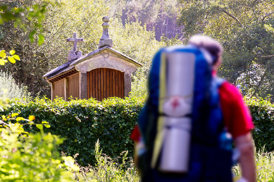 way to Santiago of Compostela ,pilgrim unfocused with backpack and scallop shell sign in english route , near Mino village , Coruna , Spain