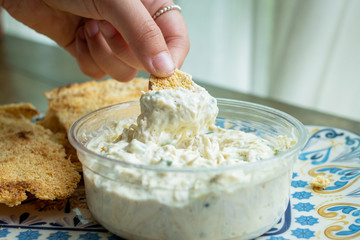 mujer toma una muestra de dip de pollo con casabe concepto comida saludable
