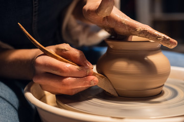 a master in a pottery workshop shows the technique of modeling a pot on a Potter's wheel