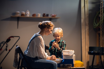 a young woman Potter helps a cute boy to make a gift for his mother out of clay