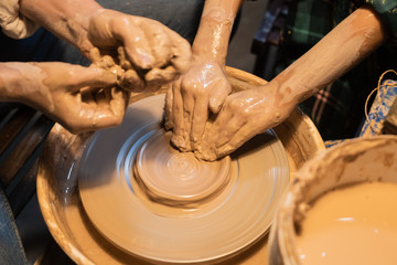 close-up of the hands of a woman and child in clay in a pottery workshop