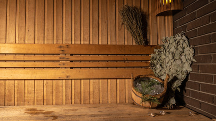 In the sauna broom and bucket against the background of the bath of wood on the side for advertising