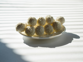 white chocolate coconut truffles on a plate against the backdrop of window shade