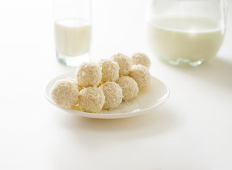 white chocolate coconut truffles on a plate against the backdrop of window shade. top view.