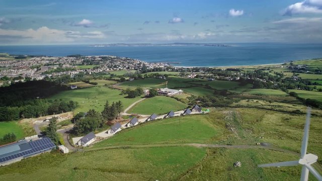 Ireland port town windmill aerial view on ocean bay. Beautiful landscape of green meadows, forests and similar white houses looking out seascape. Mesmerizing scenery shot of Ballycastle in 4K, UHD